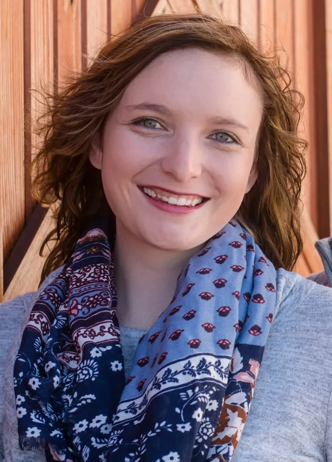 Sarah Neudorf, smiling in front of a brick wall
