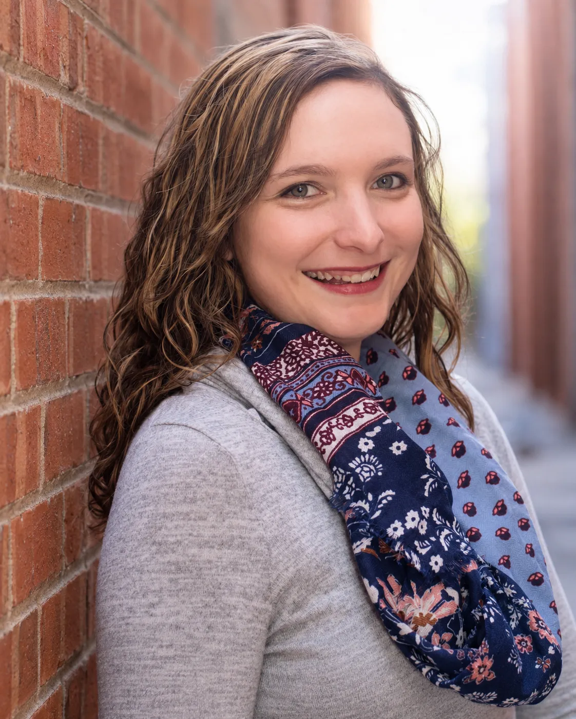 Sarah Neudorf, smiling in front of a brick wall